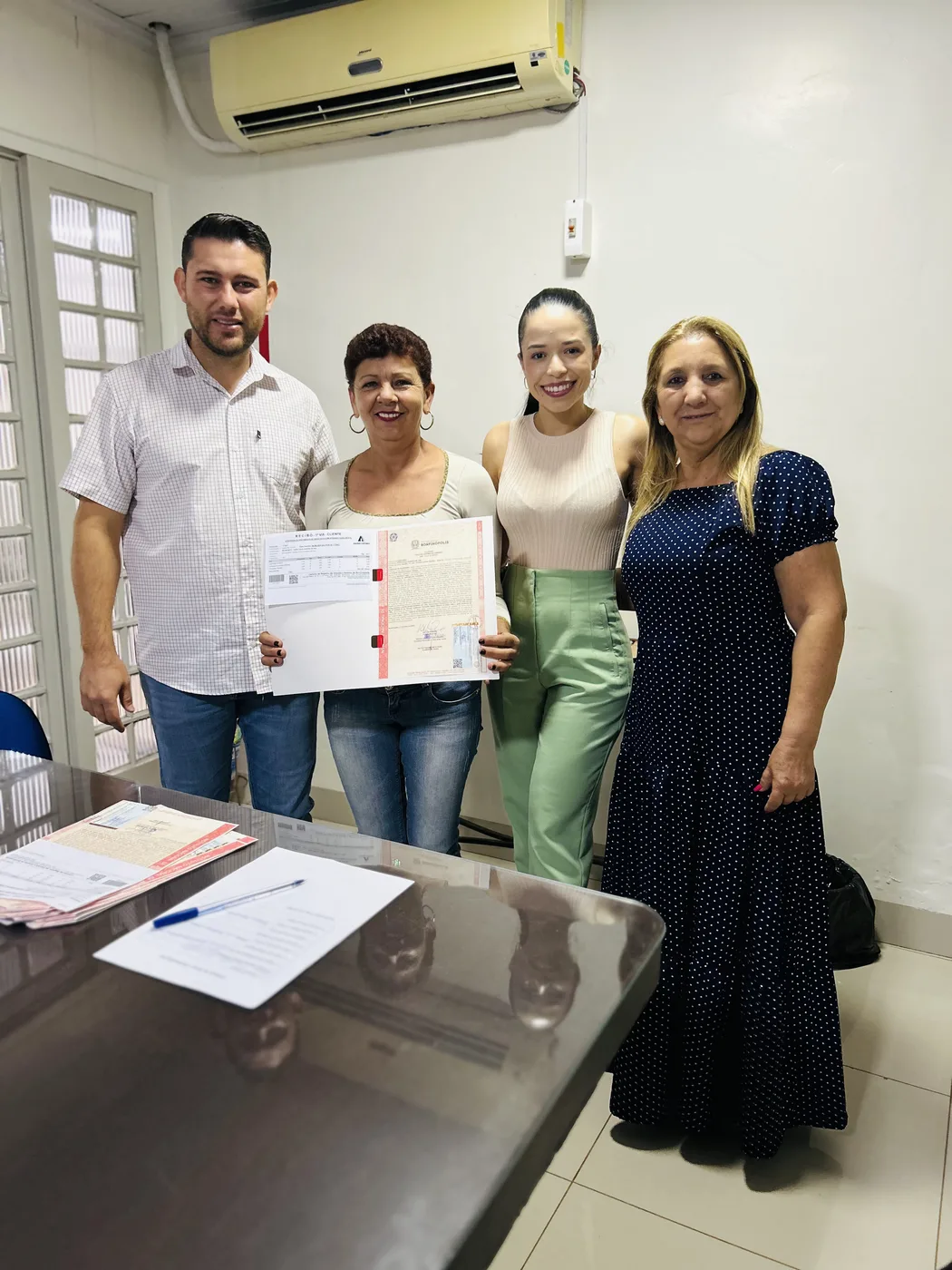 Cliente recebendo o título de REURB ao lado da equipe